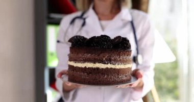 Nutritionist doctor holds sweet chocolate cake in hands. Healthy eating diet and dangers of sweets for health