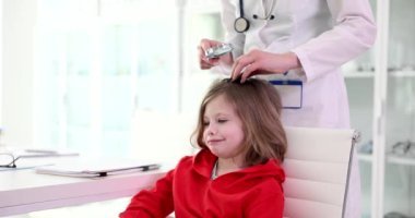 Female trichologist doctor checks children hair through magnifying glass. Pediculosis in children causes symptoms and diagnosis