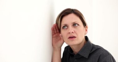 Woman pressed ear against the wall and listened attentively. Concept of gossip and eavesdrop