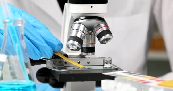 Pesquisador Detém Tira Teste Para Examinar Líquido Sob Microscópio Composição — Vídeo de Stock