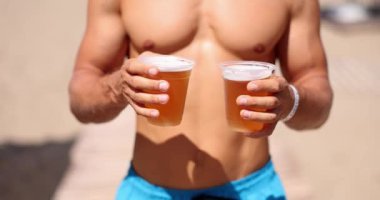 Adamın eli havuzda iki plastik bardak tutuyor. Yaz tatili ve alkol