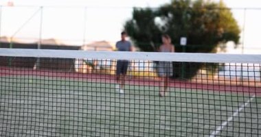 Happy couple communicate after playing tennis on court. Man and woman with tennis rackets talking outdoors