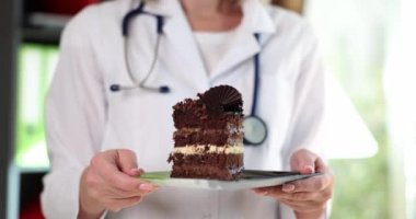 Beslenme uzmanı bir tabak çikolatalı keki elinde tutuyor. Doktor abur cubur ve obeziteye karşı uyardı.