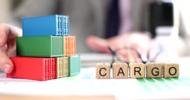Business man moves stack of cargo containers on office table. Container shipping import and export