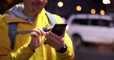 Turistin elleri turist rotası aramak için gece vakti cep telefonu kullanıyor. Adam cihaz monitörüne bakıyor mesajları kontrol ediyor.