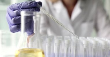 Test tüpüne temiz sıvı damlaları damlatıyor. Tıbbi araştırmalar ve yağlarla yapılan kozmetik deneyler