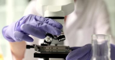 Bilim adamının eli, mikroskop ve objektif göz merceğinin ayarlanması ve ayarlanmasına yakın çekim. Laboratuvarda mikrobiyolojik test için mikro polis kullanan bir bilim adamı.