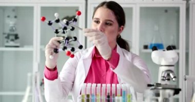 Female scientist student pointing at molecular model in laboratory. Scientific research and education