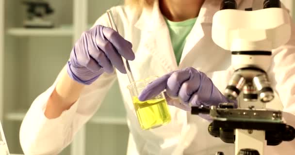 化学者は化学実験室で黄色の液体と手のフラスコを保持し 石油化学製品の品質管理 — ストック動画