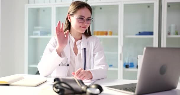 网上医生在网上视频会议上问候女病人 全科医生在手提电脑前挥手打招呼 — 图库视频影像