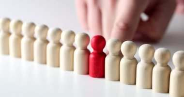Red wooden figure in row of white identical wooden figures in row. Concept and individuality in team