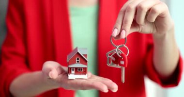 Woman realtor holds key and a house in hands closeup. Social housing mortgage and home purchase