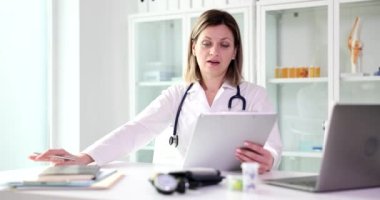 Upset female doctor looks at medical documents. Bad medical news and diagnosis