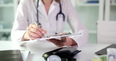 Female doctor fills out medical forms and health insurance. Hands of nurse therapist with pen on medical documents