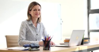 Pretty business woman smiling at camera sitting at desk in front of computer. Successful business consultant