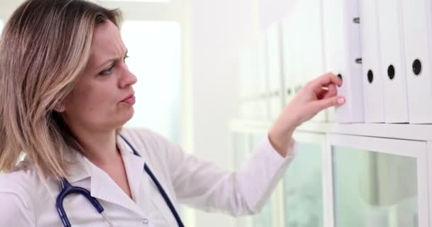 Enfermera Médica Pensativa Que Busca Carpeta Con Documentos Médicos Archivo — Vídeo de stock