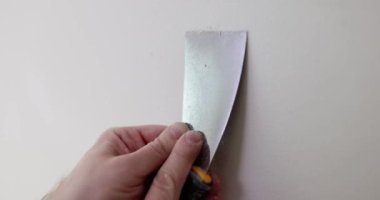 Metal spatulayla duvardaki boyayı çıkarıyorum. Evde küçük boyama işleri.