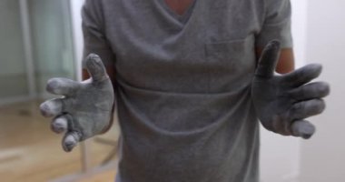Carpenter or master grinder cleans work gloves from dust. Construction worker in protective gloves clapping hands
