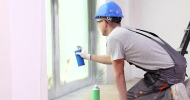 Usta sprey kutusundaki aerosol akrilik diş minesiyle pencere yamacını boyuyor. Pencere çerçeveleri boyanıyor