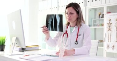 Doktor ellerinin röntgenini ve iskelet ellerinin modelini tutuyor. Ellerin eklemlerinde ağrı