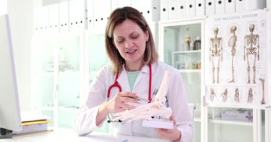 Orthopedic doctor shows model of plastic human foot. Joint aches arthritis causes diagnosis and treatment