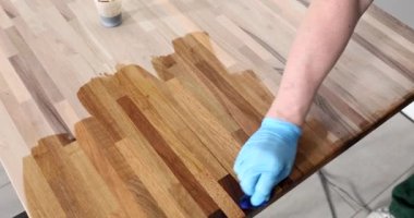 Worker in gloves oiling wooden board closeup 4k movie slow motion. Furniture production concept