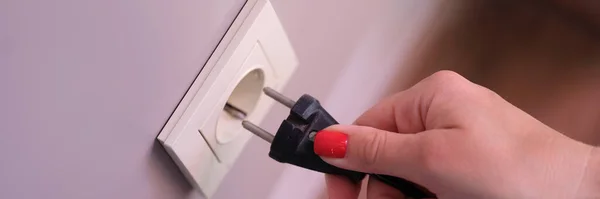 Hand inserts plug into socket closeup. Use of promising energy in home concept