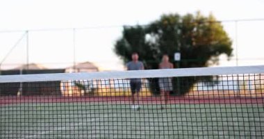 Man and woman in sportswear walk around court. Tennis players getting ready to play tennis