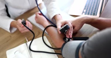 Kardiyolog doktor klinikte tonometresi olan hastaya kan basıncını ölçüyor. Atardamar hipertansiyonu ve kalp sorunları teşhisi