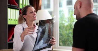 Doctor woman explains x-ray of patient lungs in clinic. Inflammation of lungs and treatment of patients