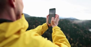 Male photographer takes pictures with digital camera in mountains. Blogger is engaged in creative photography amateur filming