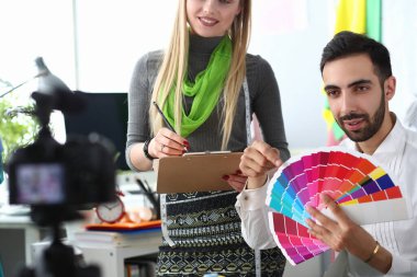 Fashion designers woman and man chooses color from a palette to camera. Creative workspace with color swatches and offline designer fashion blog clipart