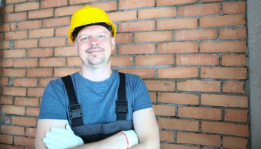 Young smiling handsome constructor builder foreman folding hands. Construction quality services and profession of builder