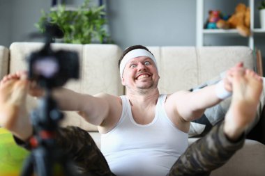 Sports male blogger doing morning exercises warming up in living room in front of camera. Sports online blog for maintaining ideal body shape