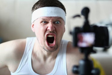 Emotionally angry sports blogger man screaming at camera. Sport motivation perseverance and remote training concept