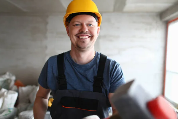 Portrait of smiling builder at construction site with sledgehammer in hands. Construction quality services and profession of builder