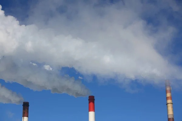 火力发电厂三根带蒸汽和烟雾的管子在暖气季节对着蓝天 Chp工作概念 — 图库照片