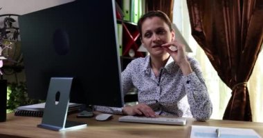 Ofisteki sinirli iş kadını çivi yiyor ve bilgisayarla çalışıyor. Tırnak yeme onyehofajisi semptomlara neden olur.