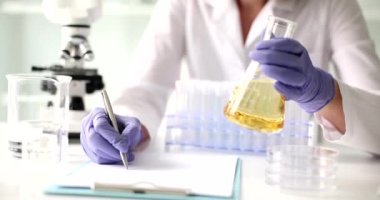 Bilim adamı, mataradaki saydam sarı sıvıyı laboratuvar testine tabi tutuyor. Kozmetik yağların kimyasal uzmanlığı