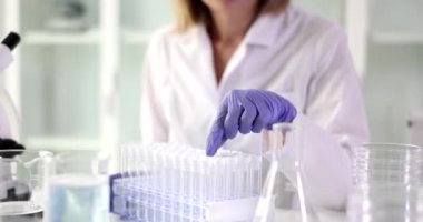 Bilim biyoloğu laboratuarda test tüpü arıyor. Kimyasal ekipman çanakları ve reaksiyonlar