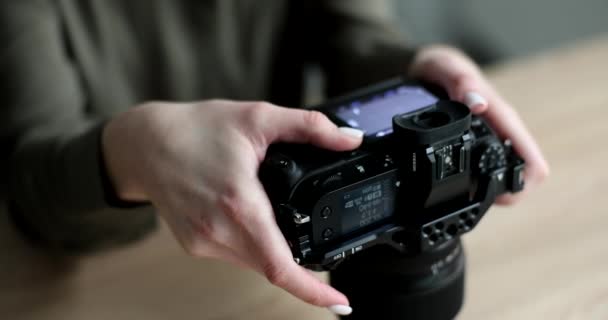 黒いプロのカメラのクローズアップ4K映画スローモーションの写真を見ている女性写真家 趣味写真の概念 — ストック動画