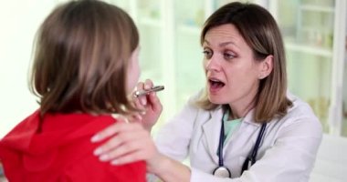 Klinikte çocuğun boğazının doktor tarafından incelenmesi. Çocuklarda ve viral bademcik iltihabı.