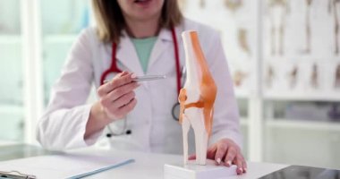 Ortopedik doktor diz ve tendonun anatomik modelini gösteriyor. Travma ve kemik eklem iltihabı cerrahi muayenesi