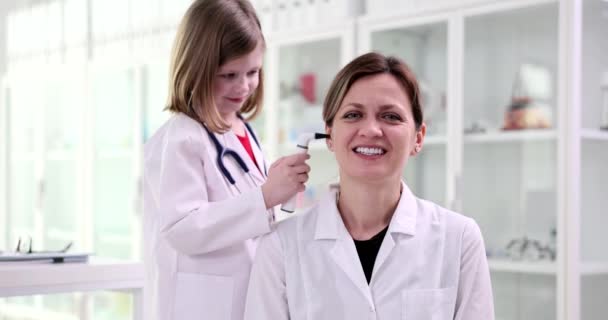 小児科医の女の子は女性医師のEntに聴診器の耳で見えます フレンドリーな医師の子供の連絡先と医学教育 — ストック動画