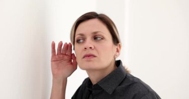 Meraklı bir kadının portresi, duvarın arkasından dikkatlice dinlerken göze göz hareketi yapıyor. Haber ve dedikodu.