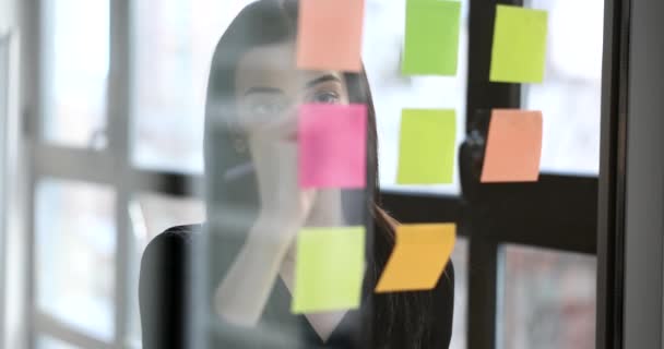 经理女士在办公室4K电影慢镜头的彩色玻璃贴纸上写提醒 业务概念方面的工作安排 — 图库视频影像