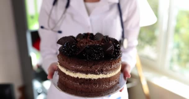 栄養士は 高カロリー不健康な砂糖食品を放棄することをお勧めします 医師や看護師はチョコレートケーキを保持し 過剰摂取に対して警告します — ストック動画