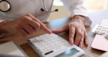 Doktor tüm masrafları hesaplamak için hesap makinesi kullanıyor. Sağlık sigortası maliyeti
