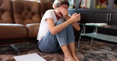 Depresyon ve nevrozdan muzdarip bir kadın yerde oturup ağlıyor. Aşırı stres ve hormon yetmezliği.