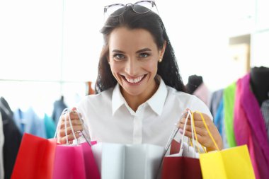 Parlak alışveriş torbalarıyla tatmin olmuş mutlu kadın paketler alıyor ve indirimlerden hoşlanıyor. Gülümseyen kız bayram indirimi için hediye almış.